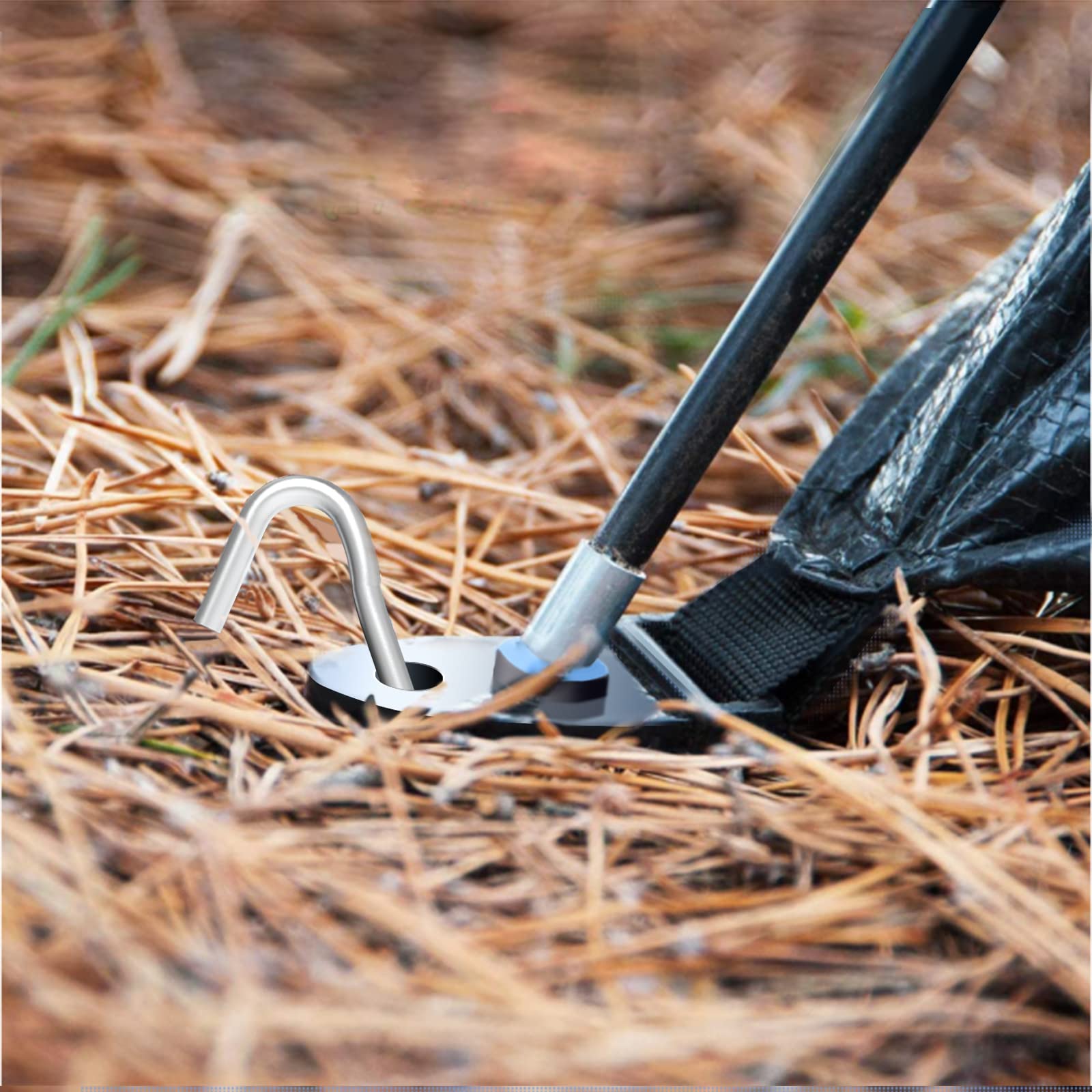Securing a canopy leg to the ground using a 9-inch metal tent stake in sandy soil at a campsite